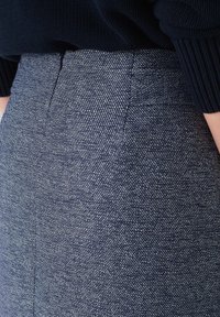 Hoog-getailleerde donkere denim broek met een subtiel textuurpatroon, rechte pasvorm en schone naden. Geen zichtbare sluitingen.