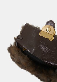 Borsa a tracolla in finta pelle marrone con bordi in pelliccia. Presenta una chiusura con logo dorato e una zip, evidenziando una texture lucida.