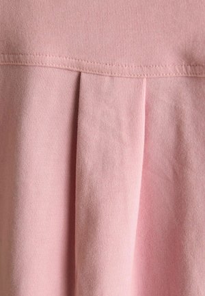 Roosa puuvillakangas tekstuuriga pinnaga, mis sisaldab horisontaalset õmblust ja vertikaalseid voldikuid lisadetailideks.