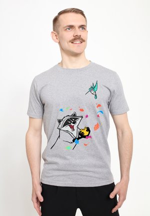 Grijze katoenen t-shirt met een afbeelding van een wasbeer die een geel voorwerp vasthoudt, versierd met kleurrijke bladeren en een klein vogeltje.