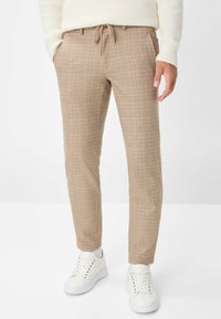 Beige geblokte broek met een relaxte pasvorm, een tailleband met trekkoord, zijzakken en een enkelvoudige zoom, gecombineerd met witte sneakers.