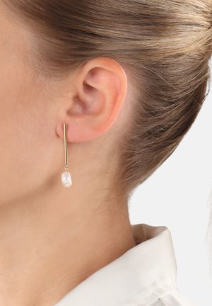 Goldene Ohrringe mit einem langen, schlanken Balkendesign und einem einzelnen unregelmäßigen weißen Perlenanhänger, der elegant nahe dem Ohrläppchen hängt.