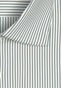 Colletto della camicia a righe con strette strisce verticali grigie e bianche, con tessuto liscio e dettagli di cucitura visibili.