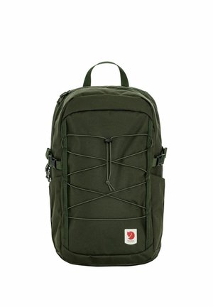 Donkergroene rugzak met elastisch koord aan de voorkant, zijgespen, bovenhandvat en een klein rood voslogo patch rechtsonder.