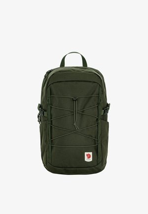 Donkergroene rugzak met elastisch koord aan de voorkant, zijgespen, bovenhandvat en een klein rood voslogo patch rechtsonder.