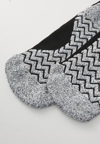 Črne in sivo pletene nogavice z vzorcem v cik-cak, z teksturiranimi sivimi prsti in enotno črnim zgornjim delom.