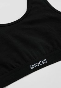 Schwarzes, kurzes Bralette aus weichem Stoff mit rundem Ausschnitt und gerafftem Bund, auf dem "SNOCKS" in Weiß gestickt ist.