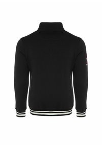 Crna zip-up dukserica s visokim ovratnikom, s bijelim i zelenim prugastim rebrastim manžetama i rubom, te malim vezom na ramenu.