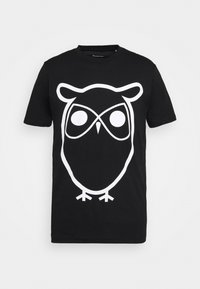 Camiseta de algodón negra con un gran gráfico de un búho blanco con ojos circulares y líneas simples, mangas cortas y cuello redondo.