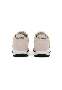Sport shoes with a suede and mesh upper in light pink and beige, featuring a white midsole and black rubber outsole. Branding on the heel.