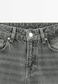 Jeans in denim grigio con una finitura sbiadita, dotati di chiusura a bottone, passanti per cintura e design a cinque tasche. Le cuciture sono in un tono grigio abbinato.