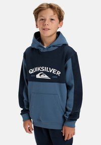 Hooded sweatshirt in dark and light blue with a kangaroo pocket and white Quiksilver logo. Made of soft fabric with a relaxed fit.