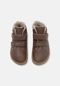 Bottes en cuir marron avec doublure en fourrure. Comprend deux sangles en Velcro ajustables, des orteils arrondis et des semelles texturées pour une meilleure adhérence.