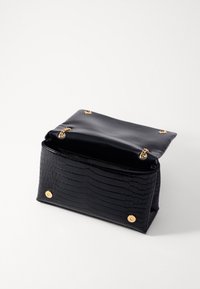 Borsa in finta pelle di coccodrillo nera con hardware dorato, aperta nella parte superiore, che mostra un esterno texturizzato e una forma rettangolare strutturata.