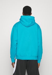 Felpa turchese con tasca a marsupio, cappuccio regolabile e polsini a coste. Realizzata in tessuto morbido, presenta una vestibilità comoda e un design semplice.