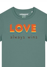 Groene katoenen t-shirt met meerkleurige tekst: "LOVE" in vet oranje, gelaagd met geel en blauw, en "always wins" in bruin.