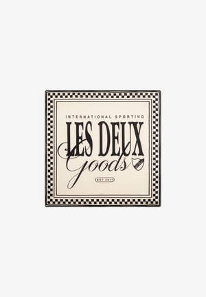 Plato cuadrado con un fondo crema y texto en negro. Un borde de tablero de ajedrez rodea "LES DEUX Goods" y "EST 2011" con un pequeño logo.