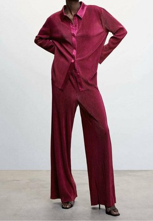 Ensemble deux pièces fuchsia comprenant une chemise à boutons avec des rayures verticales et un pantalon large, le tout en tissu doux et texturé.