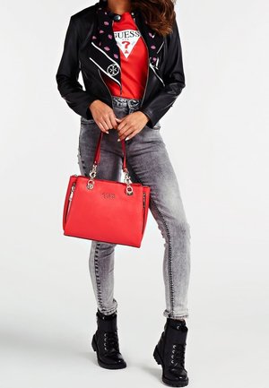 Sort faux læderjakke med hvid syning, rød håndtaske, grå skinny jeans med lynlåsdetaljer og sorte snørebånd støvler.