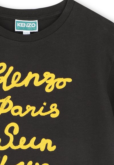 Czarna bawełniana koszulka z jasnoniebieskim haftowanym napisem "Kenzo Paris" w stylu kursywy. Szczegół wykończenia w postaci prążkowanego dekoltu.
