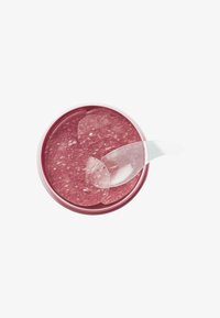 Transparante ronde container met een roze gel binnenin, voorzien van een heldere spatel en verschillende dunne, glanzende gelvellen die bovenop liggen.