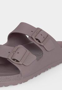Lila Birkenstock-Sandale mit zwei verstellbaren Schnallenriemen und profilierter Sohle für besseren Halt.