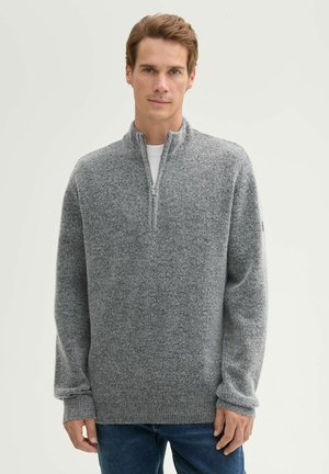 Grauer Zip-Hals-Pullover aus strukturiertem Stoff, mit langen Ärmeln und gerippten Bündchen, getragen über einem weißen Rundhalshemd.