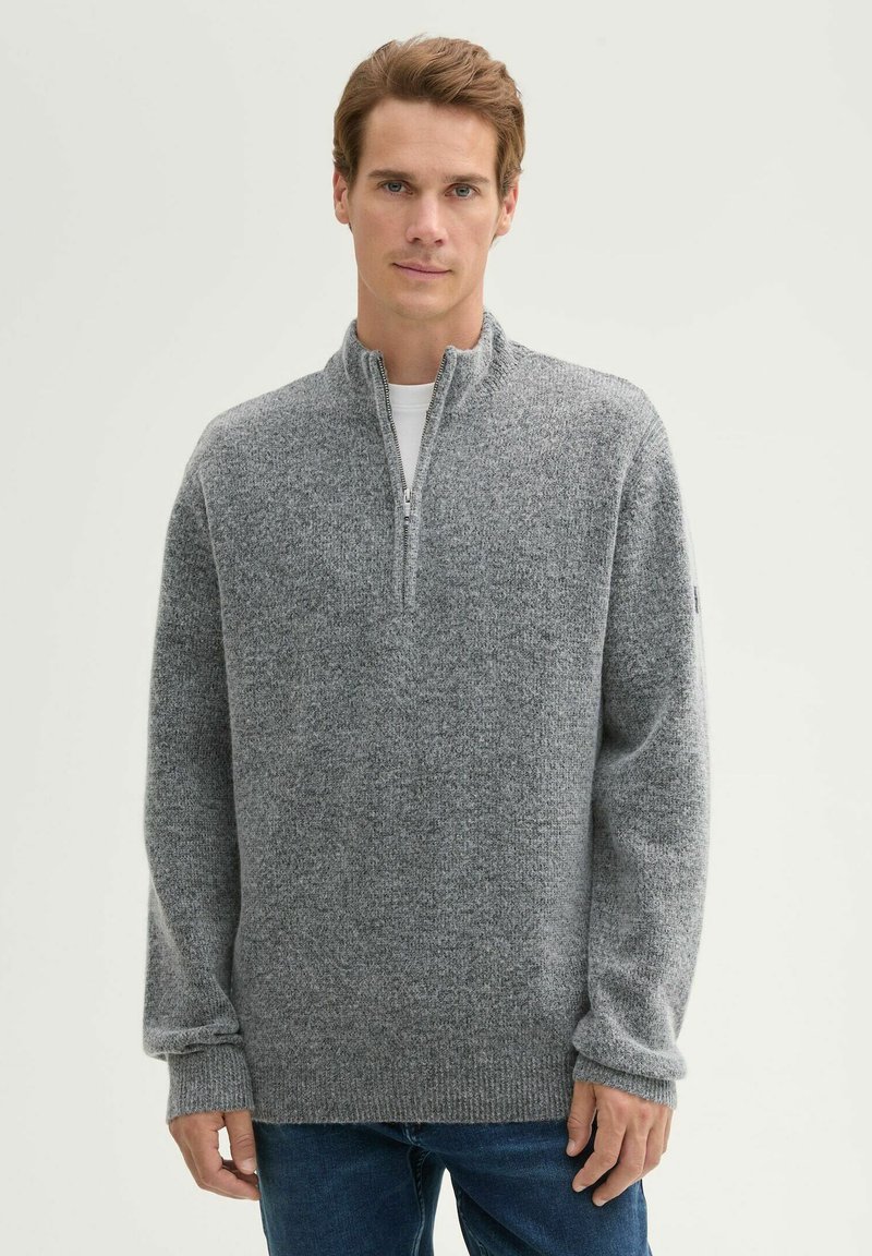 Grauer Zip-Hals-Pullover aus strukturiertem Stoff, mit langen Ärmeln und gerippten Bündchen, getragen über einem weißen Rundhalshemd.