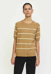 Suéter corto de manga corta a rayas marrón con cuello redondo. Presenta rayas horizontales blancas y un dobladillo acanalado. Combinado con pantalones negros.