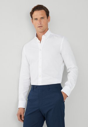 Witte overhemd met kraag, knopen en lange mouwen, gecombineerd met marineblauwe broek; zachte stof, slanke pasvorm, minimalistisch ontwerp en zonder patronen.
