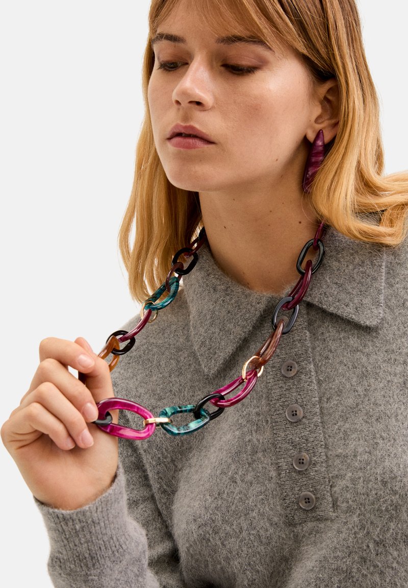 Kleurvolle, oversized ketting gemaakt van doorschijnende kunststof schakels in tinten roze, teal, bruin en zwart, met een glanzende afwerking.