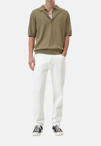 Polo shirt oliva a maniche corte con bottoni, abbinato a pantaloni bianchi e sneakers nere. Tessuto liscio, vestibilità casual, design classico.