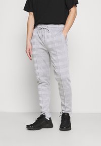 Grå joggers med rutmönster, elastisk midja med dragsko, sidfickor och avsmalnande ben, tillsammans med svarta träningsskor.