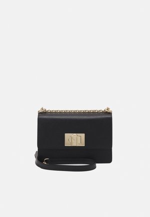 Pochette en cuir noir avec bandoulière chaîne dorée et fermoir rectangulaire doré à l'avant, présentée sur fond blanc.