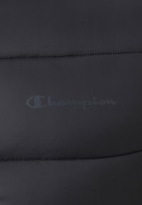 Giacca a vento nera con imbottitura, caratterizzata da cuciture trapuntate e un discreto logo Champion stampato sul tessuto, che mette in evidenza una texture liscia e lucida.