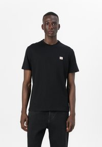 Zwarte katoenen t-shirt met korte mouwen, ronde hals en een klein geborduurd logo op de bovenste linkerborst. Eenvoudig ontwerp.