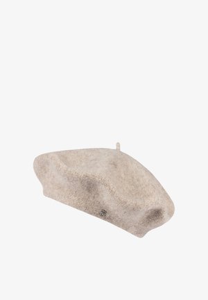 Soft beige wool beret with small stem on top and a tiny metallic emblem on the side against a white background.