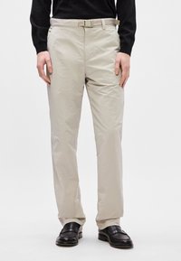 Ανοιχτόχρωμο ελαφρύ παντελόνι από απαλό ύφασμα, με κομψή γραμμή και ενσωματωμένη ζώνη. Διαθέτει πλαϊνές και πίσω τσέπες, συνδυασμένο με μαύρα παπούτσια.