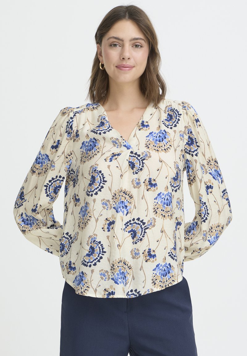 Florale Bluse in Creme mit blauen und braunen Mustern, mit V-Ausschnitt, langen Ärmeln und strukturierter Stoffqualität.