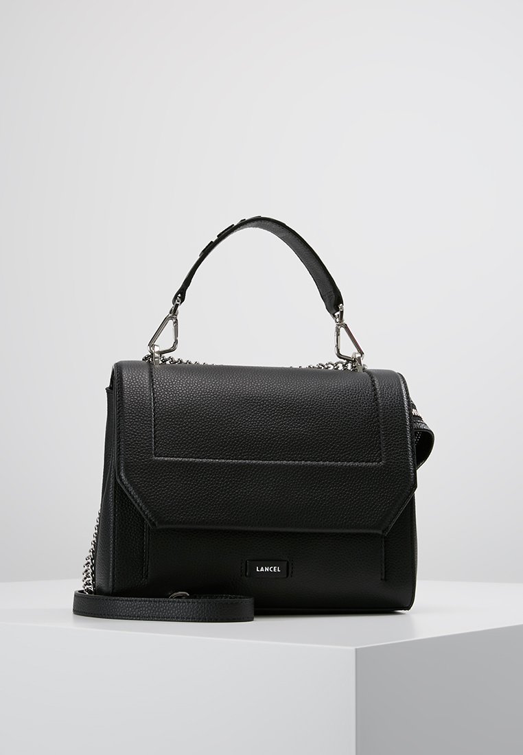 Sac à main en cuir texturé noir avec une poignée supérieure, une bandoulière amovible et des accents en métal argenté. Présente un design structuré.