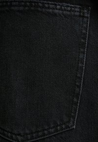 Mustat farkkukangas, jossa on takatasku; rakenne on sileä ja reunassa näkyy ompelu. Materiaali n äyttää hienoa kudontakuviota.