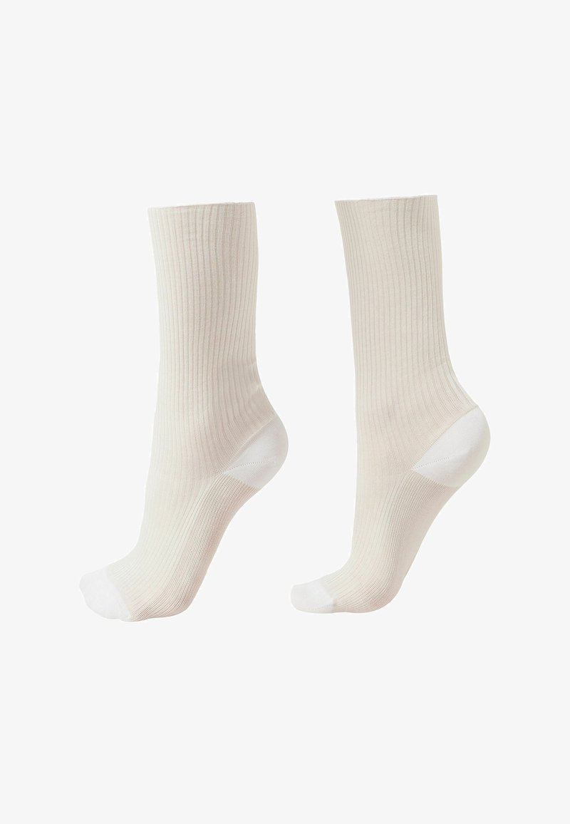 Paire de chaussettes montantes côtelées blanc cassé avec talon et pointe renforcés blancs, présentées debout sur un fond blanc.