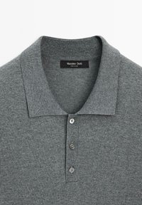 Polo grigio realizzato in morbido tessuto a maglia. Presenta un colletto classico, patta con quattro bottoni e un'etichetta che indica il marchio Massimo Dutti.