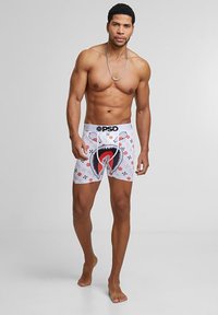 Boxershorts i vitt med en hajgrafik i röd och svart. Har en svart midja med varumärket "PSD" i vitt. Slät yta.