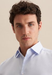 Camicia a righe blu chiaro con colletto strutturato e bottoni, caratterizzata da righe bianche verticali e una superficie liscia.