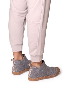 Hallgrå ankle-boots, mille leidude ja dekoratiivsete kudumistega. Omab tekstureeritud korke põhja. Kombineeritud heledate roosade spordipükstega.