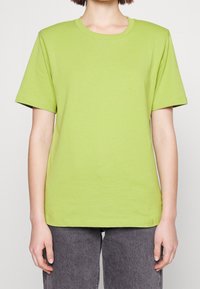 Camiseta de algodón verde con mangas cortas, cuello redondo y un corte holgado. Destaca por su textura suave y diseño sencillo.