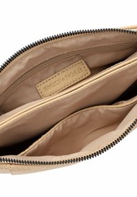 Beige leather wallet interior with tan fabric lining, featuring multiple compartments and a black zipper. Subtle embossed branding visible.
