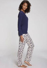 Navy long-sleeve top paired with cream pants featuring a dark blue abstract pattern. Cotton material with a relaxed fit and straight leg design.