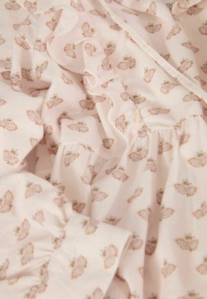 Tissu rose pâle avec un petit motif floral en orange et marron. Présente des bords froncés et une texture douce, idéal pour des vêtements légers.